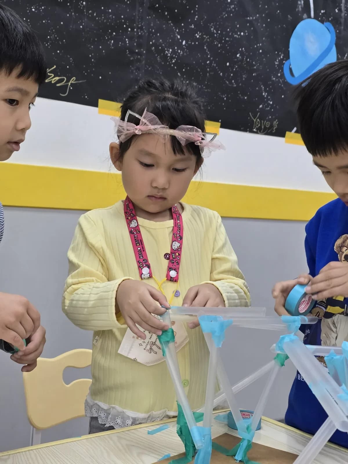 Three children joining tubes and tape during an engineering challenge