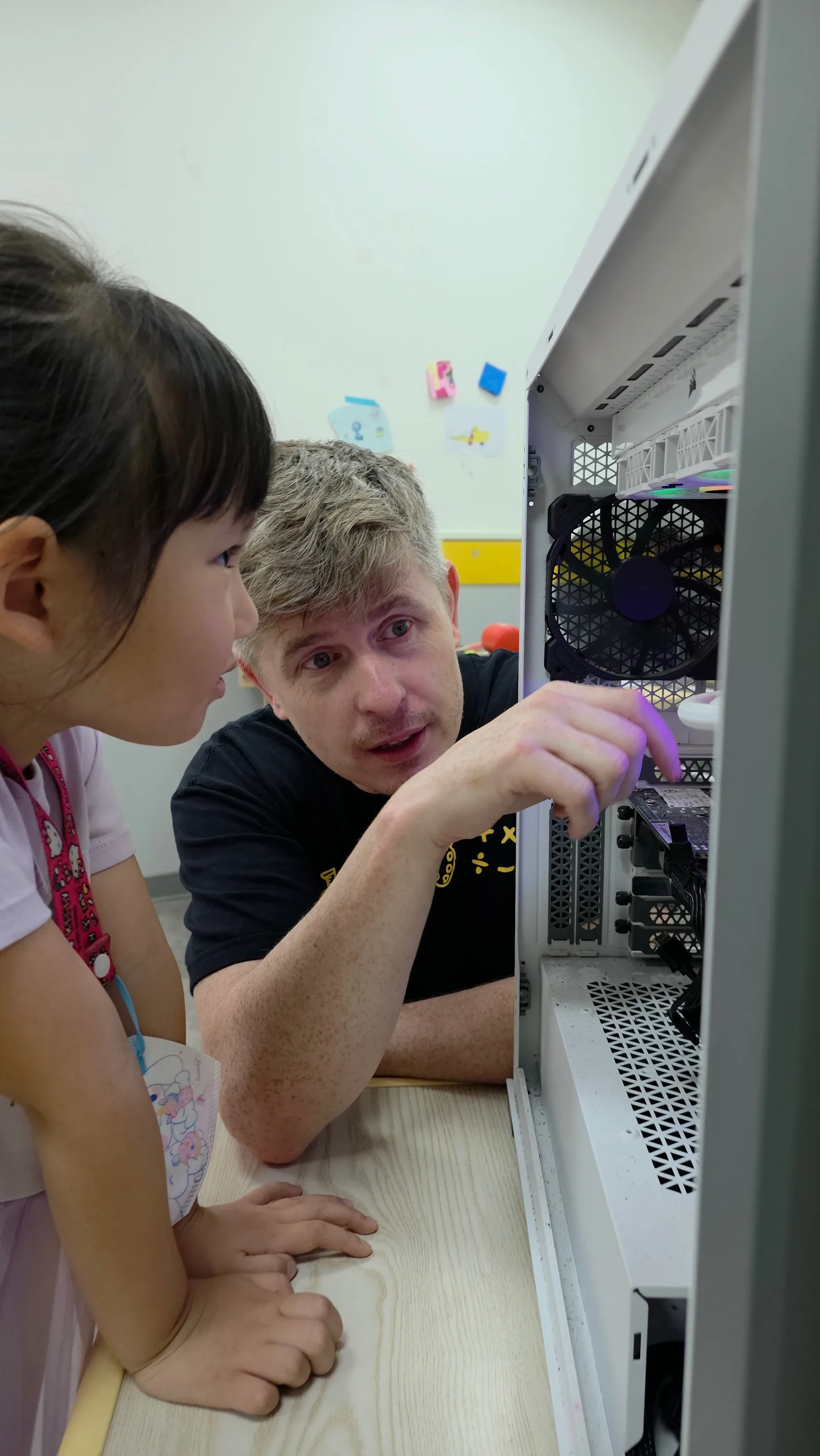 A teacher and student looking inside a working desktop computer
