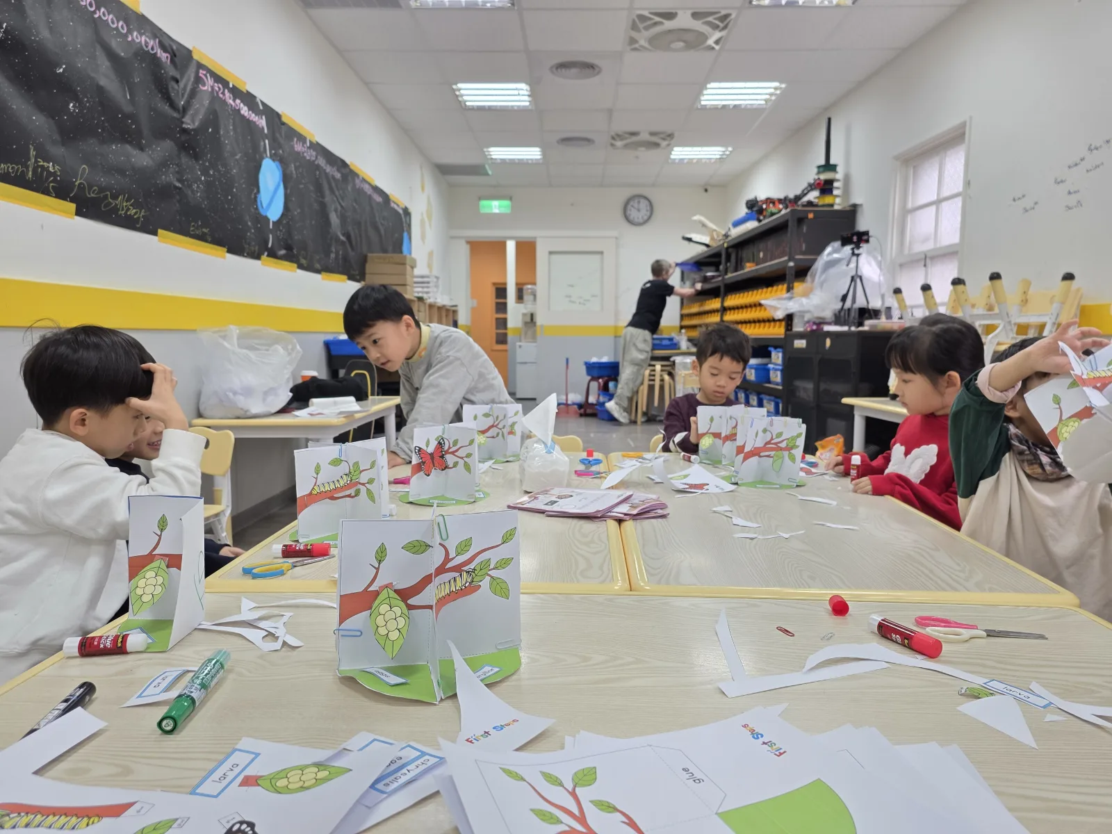 Children assembling butterfly life-cycle paper models in First Steps