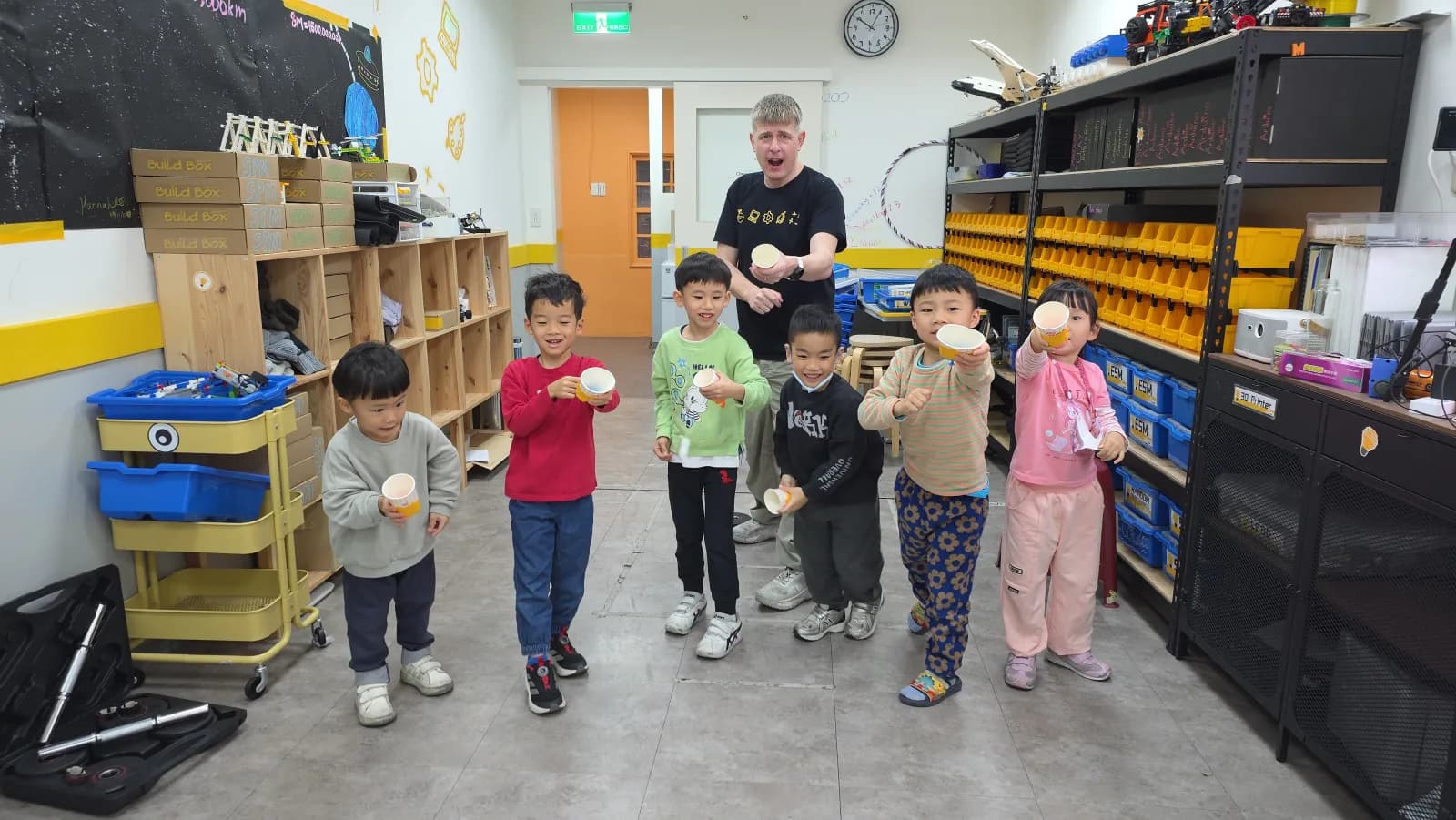 First Steps students and their teacher holding paper cups during a sound experiment