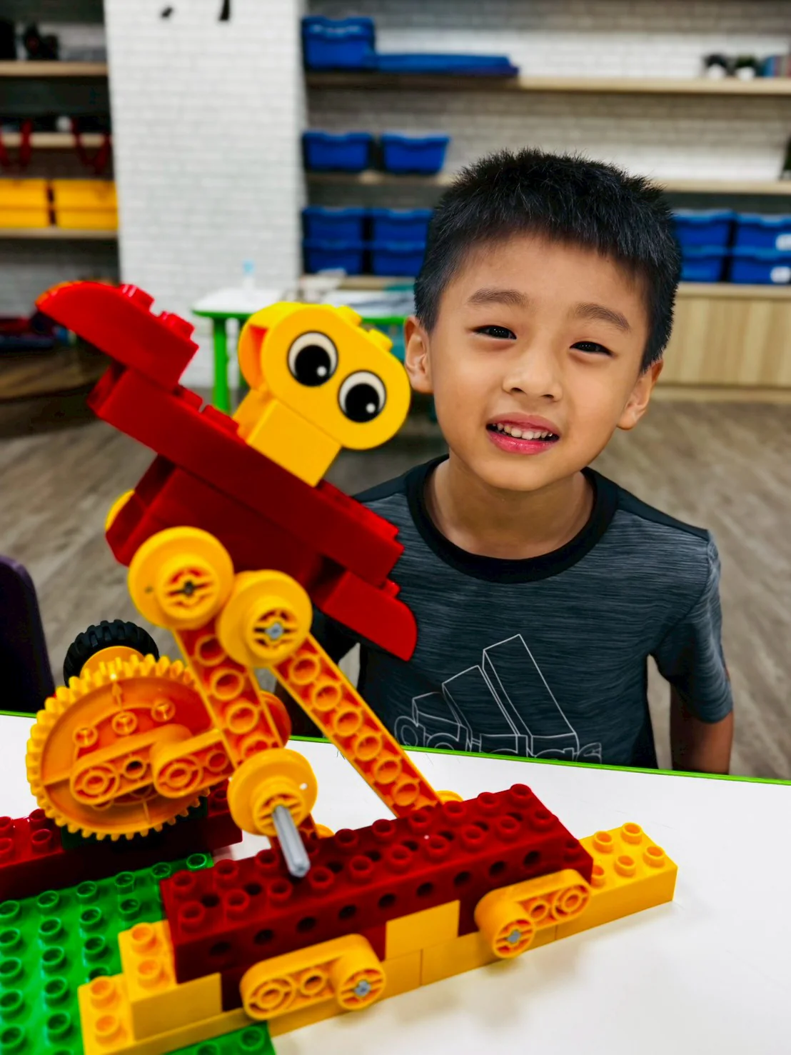 An ESM student presenting a large red and yellow LEGO Dancer model